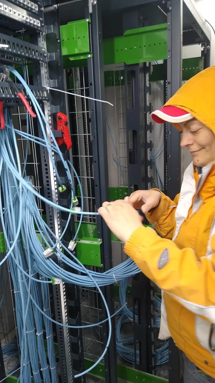 Mihaela câblant un rack serveur à l'ONSS Charleroi